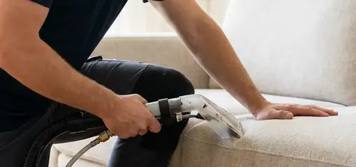 Professional upholstery cleaner deep-cleaning a fabric sofa with a handheld extraction tool, Tacoma, WA.